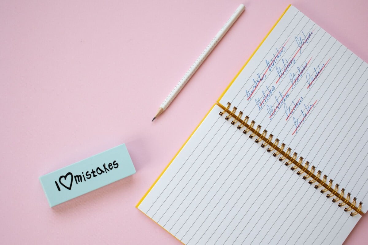 flat lay of a spiral notebook and eraser on a pastel pink background with crosse | Two Scots Abroad Flat lay of a spiral notebook and eraser on a pastel pink background with crossed out words.