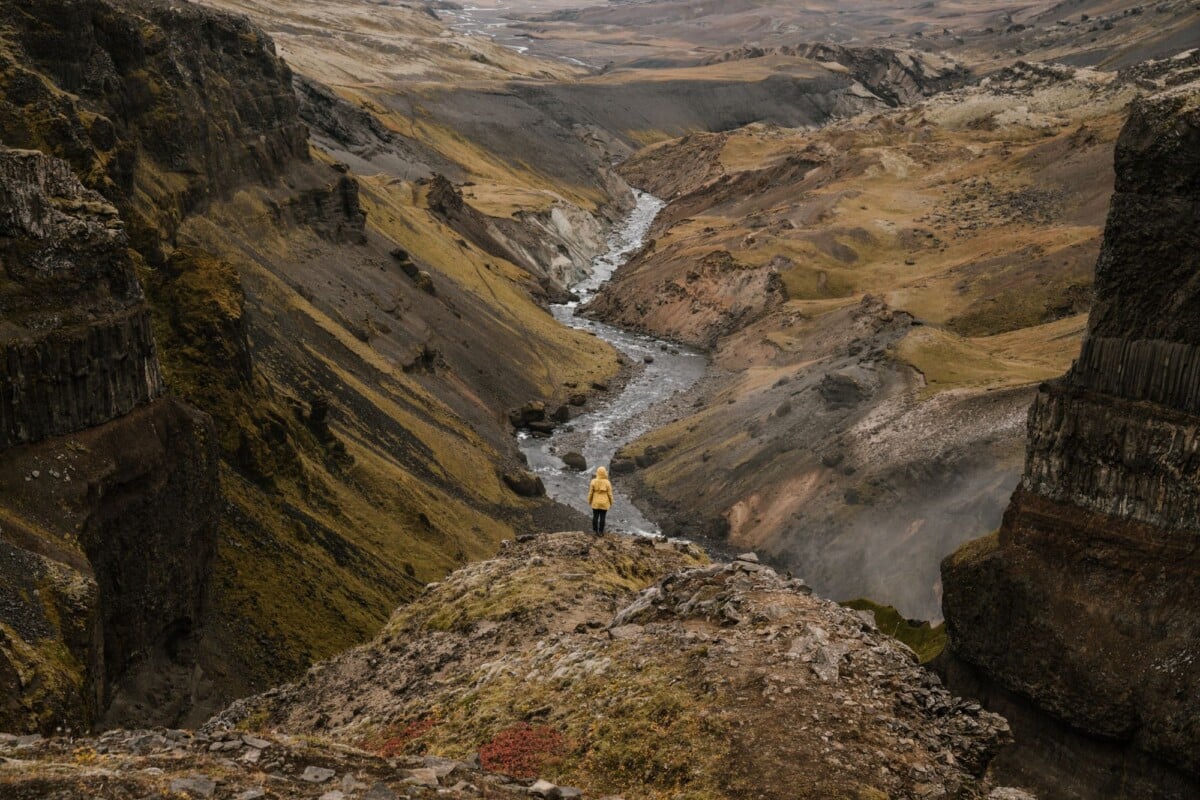 from above back view of anonymous tourist standing on rough slope in front of na | Two Scots Abroad From above back view of anonymous tourist standing on rough slope in front of narrow river flow between mounts in afternoon