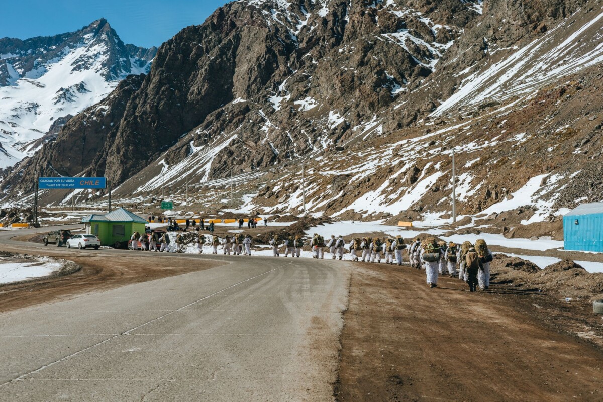 group of trekkers with backpacks hiking through snowy andes mountain pass toward | Two Scots Abroad Group of trekkers with backpacks hiking through snowy Andes mountain pass towards Chilean border.