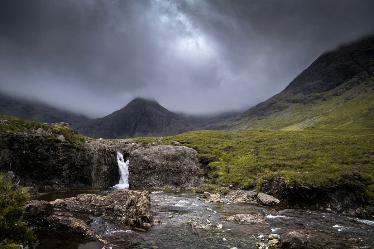 Moody scenery of a waterfall in the Isle of Skye under storm clouds.