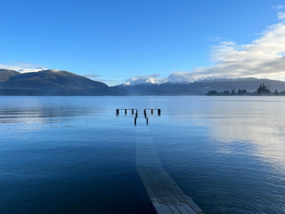 peaceful lake with a distant view of snow covered mountains in southland new zea | Two Scots Abroad Peaceful lake with a distant view of snow-covered mountains in Southland, New Zealand.