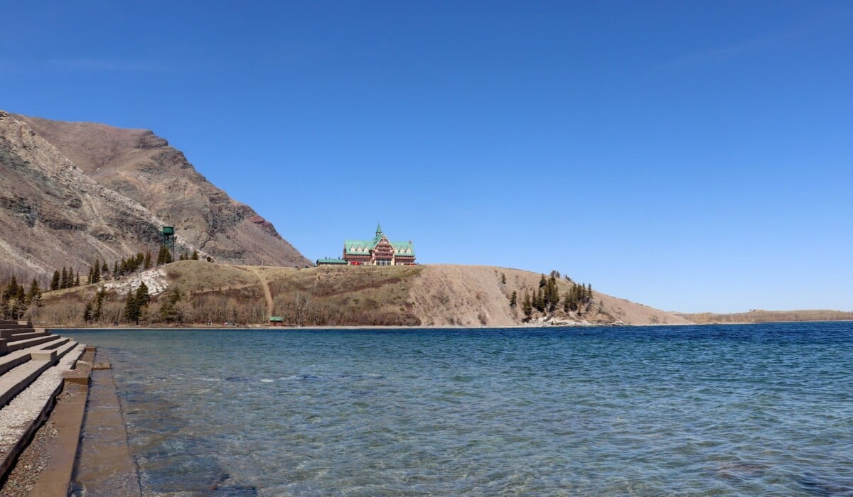scenic view of prince of wales hotel overlooking waterton lake under a clear blu | Two Scots Abroad Scenic view of Prince of Wales Hotel overlooking Waterton Lake under a clear blue sky.
