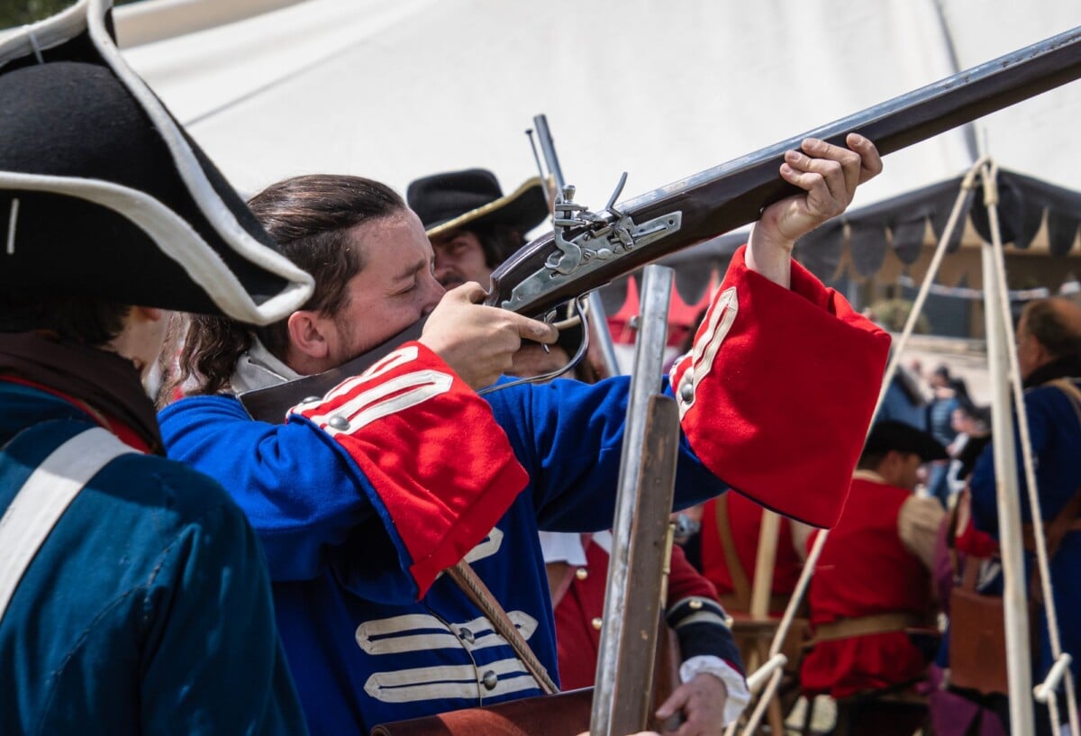 soldiers in vibrant uniforms reenacting a historical battle with muskets outdoor | Two Scots Abroad Soldiers in vibrant uniforms reenacting a historical battle with muskets outdoors.