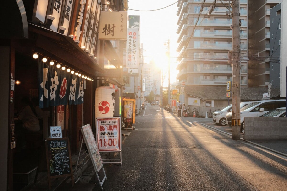 street view of urban japan with traditional signs and sunset light casting long | Two Scots Abroad Street view of urban Japan with traditional signs and sunset light casting long shadows.