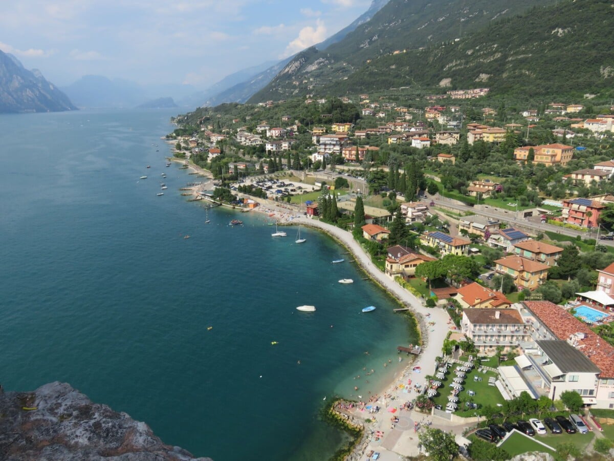 Stunning aerial view of Lake Garda, Italy showcasing waterfront, lush greenery, and mountain backdrop.
