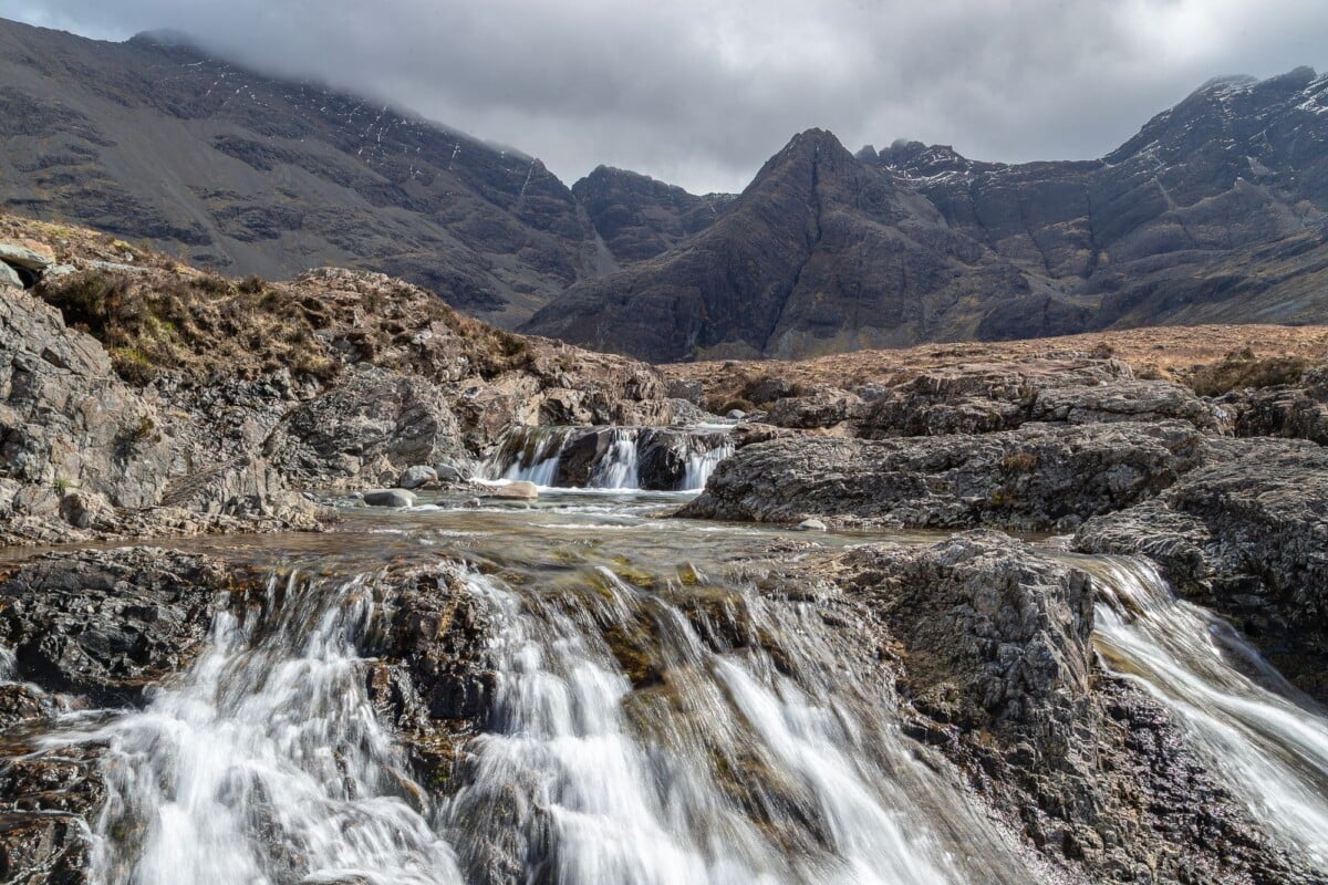 Stunning view of the Fairy Pools with cascading waterfalls and rugged mountains in Scotland.
