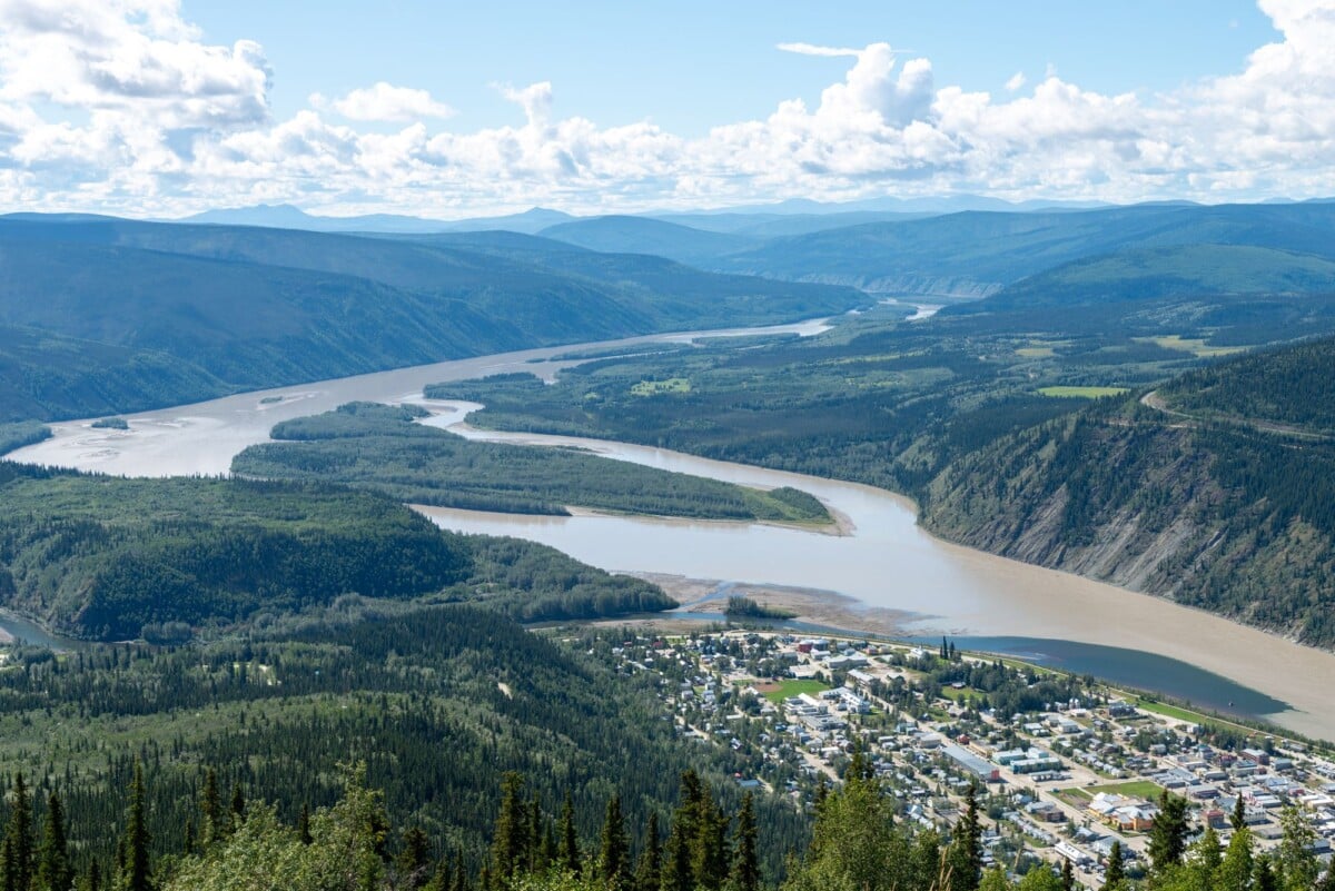 A breathtaking aerial shot of Dawson City, Yukon, Canada with the scenic Yukon River winding through lush green valleys.