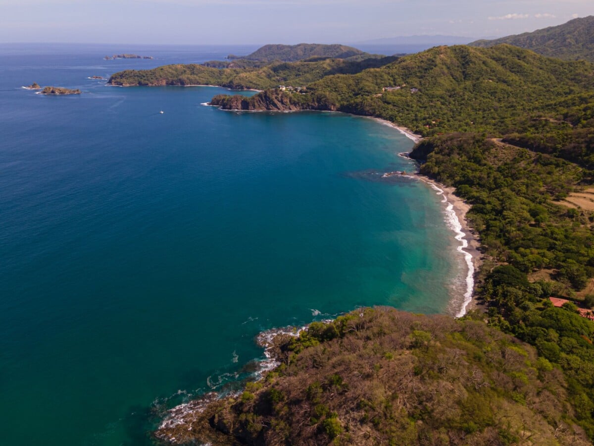A wooded Guanacaste coastline beside blue Pacific water