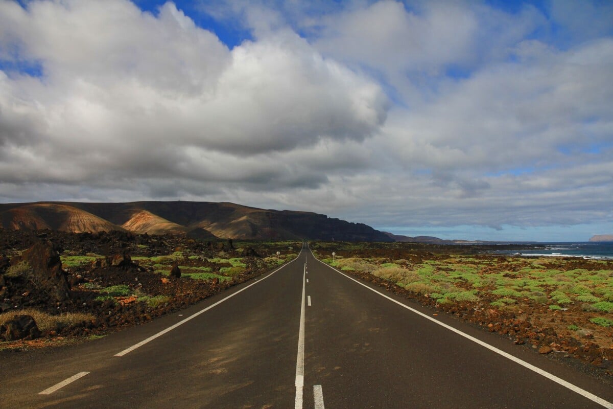 a long empty road stretches through a unique rocky landscape under a cloudy sky | Two Scots Abroad A long empty road stretches through a unique rocky landscape under a cloudy sky.