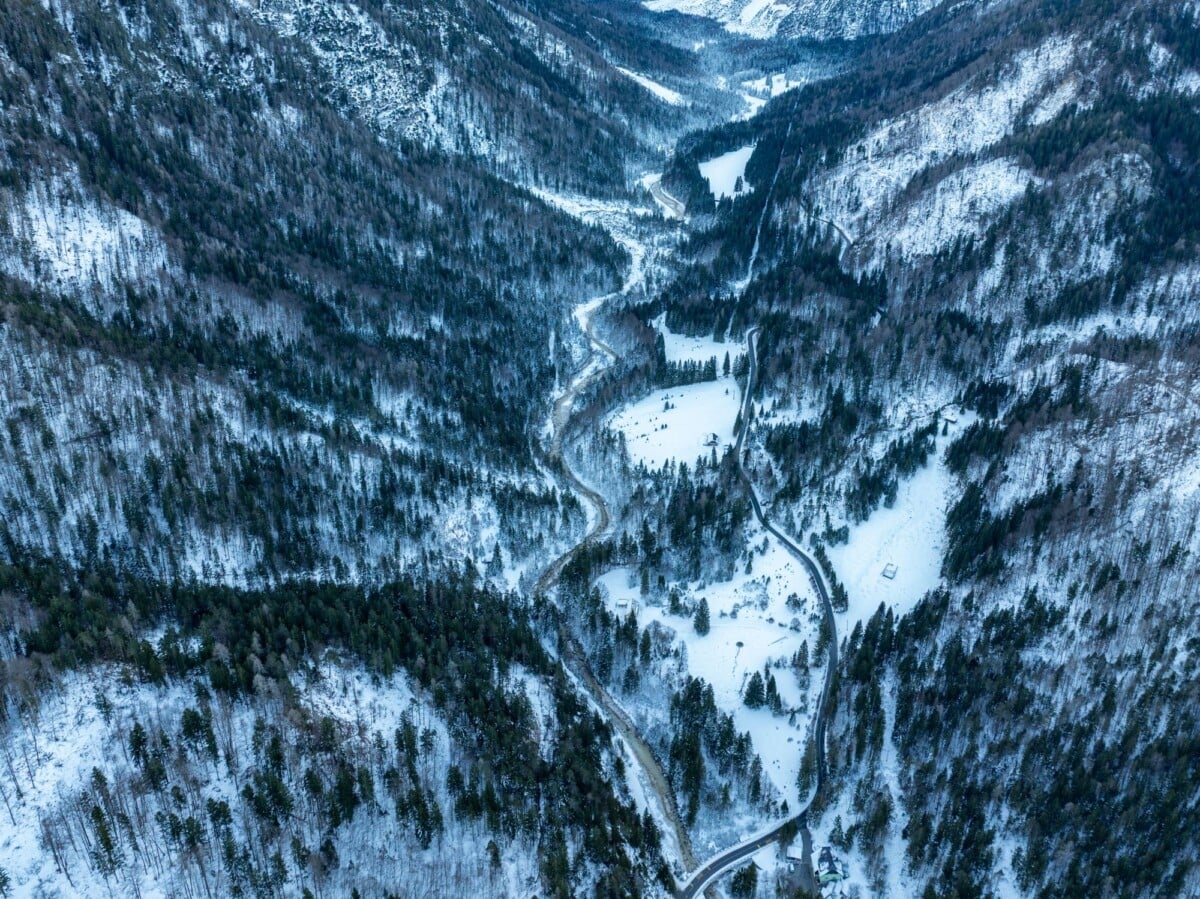 Breathtaking aerial view of the snow-covered valley and winding road in Kranjska Gora, Slovenia.