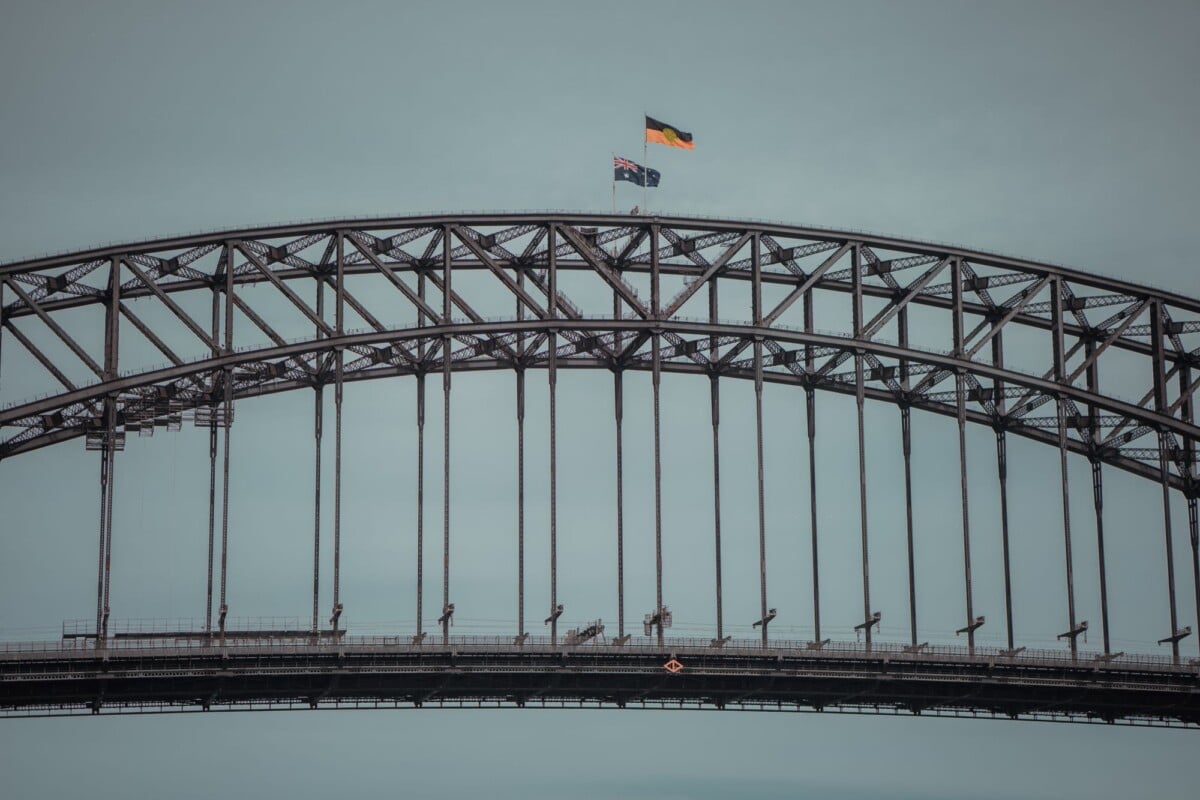 Close-up of Sydney Harbour Bridge with flags above the steel arch.