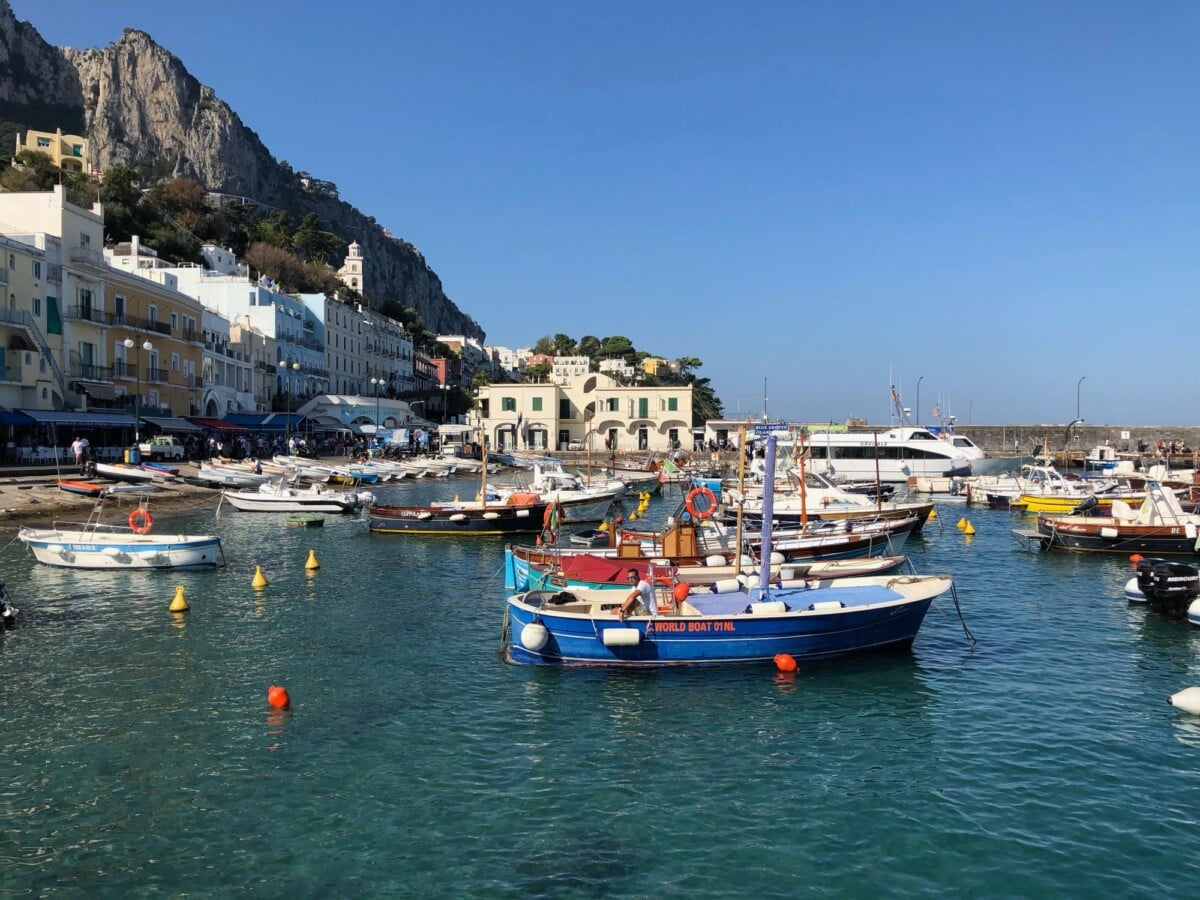 Colorful boats docked at Marina Grande in Capri under clear blue skies.