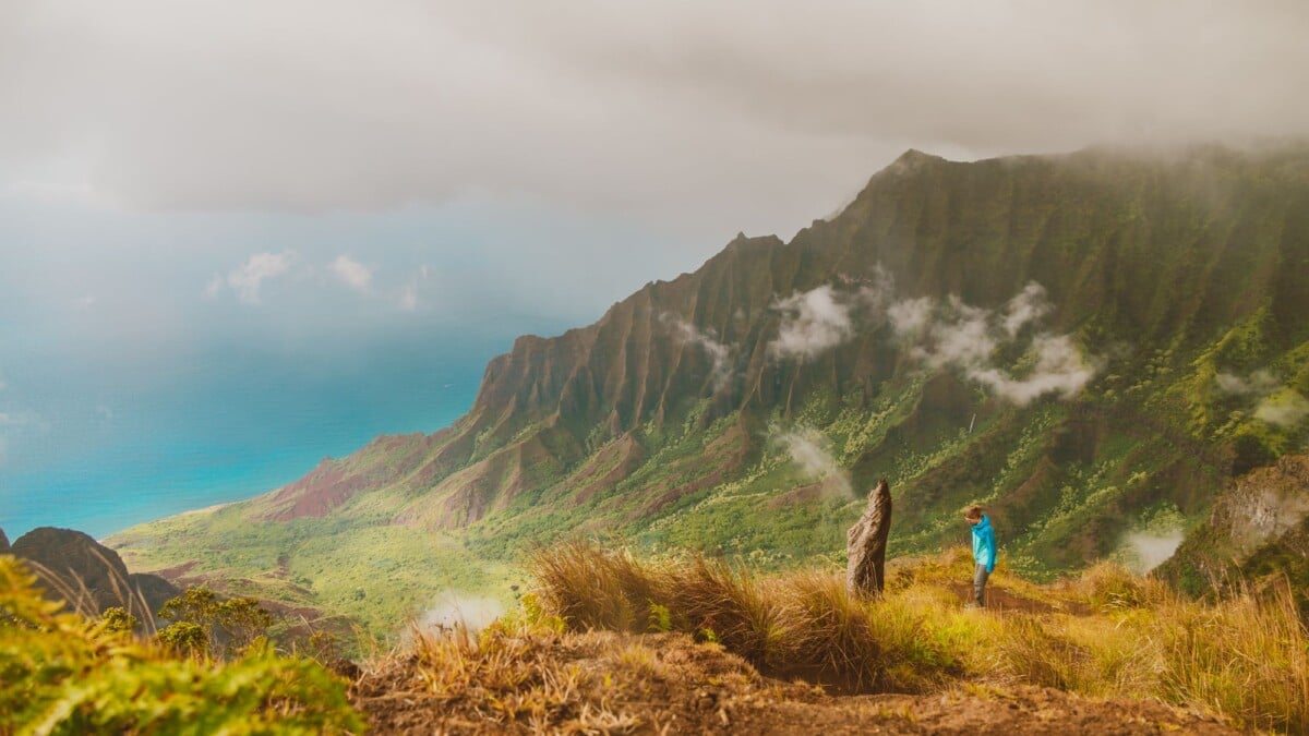 hiker gazing over the misty na pali coast in kauai hawaii capturing adventure an | Two Scots Abroad Hiker gazing over the misty Na Pali Coast in Kauai, Hawaii, capturing adventure and nature's beauty.