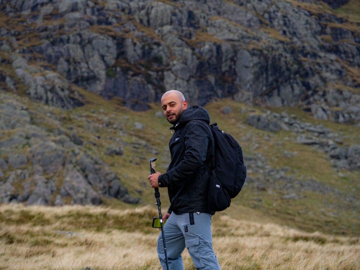 man hiking with a backpack and trekking pole in rugged rocky mountain terrain | Two Scots Abroad A walker carrying a backpack and trekking pole in open mountain terrain