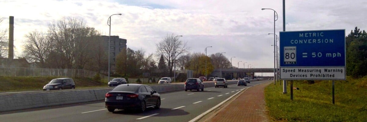 Metric Conversion on the 420: Sign advising U.S. drivers of Metricated speed limits in Canada. View is of westbound Highway 420 in Niagara Falls, Ontario at the corner of Stanley Avenue (Niagara Regio