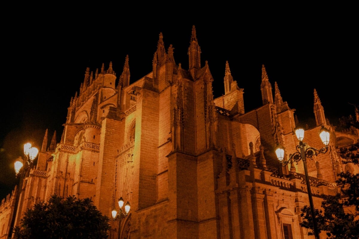 night view of the seville cathedral showcasing gothic architecture under street | Two Scots Abroad Night view of the Seville Cathedral, showcasing Gothic architecture under street lighting.