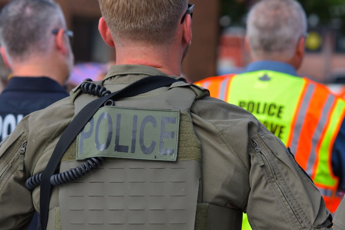 rear view of police officers in tactical gear and high visibility vests in a pub | Two Scots Abroad Rear view of police officers in tactical gear and high-visibility vests in a public setting.