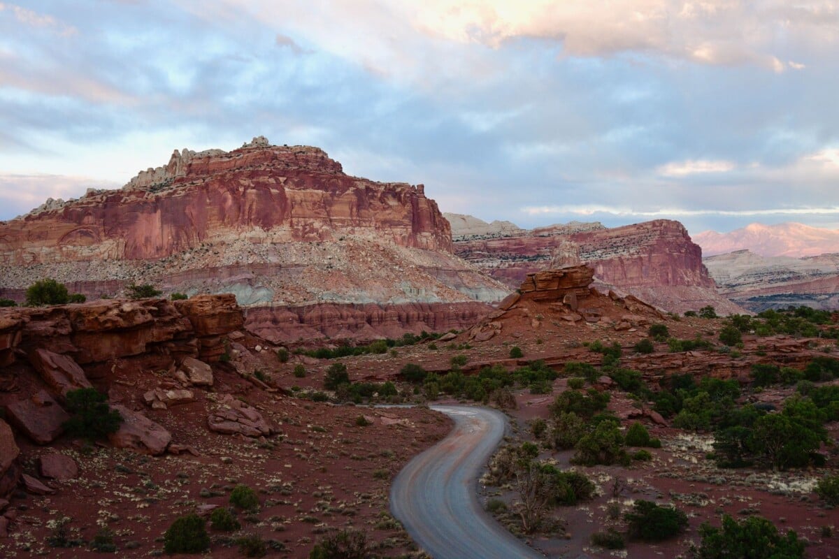 scenic view of a winding road amidst the striking red rock formations of capitol | Two Scots Abroad Scenic view of a winding road amidst the striking red rock formations of Capitol Reef National Park at sunset.