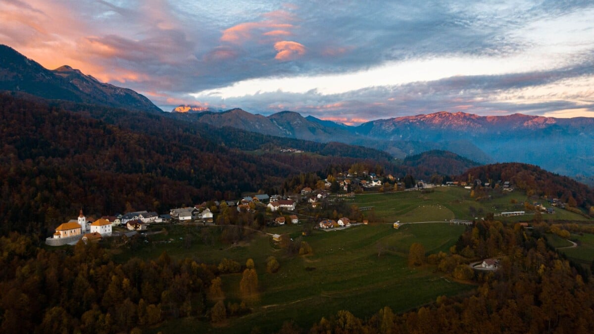 Stunning aerial view of a quaint town nestled in a valley at sunset with mountain backdrop.