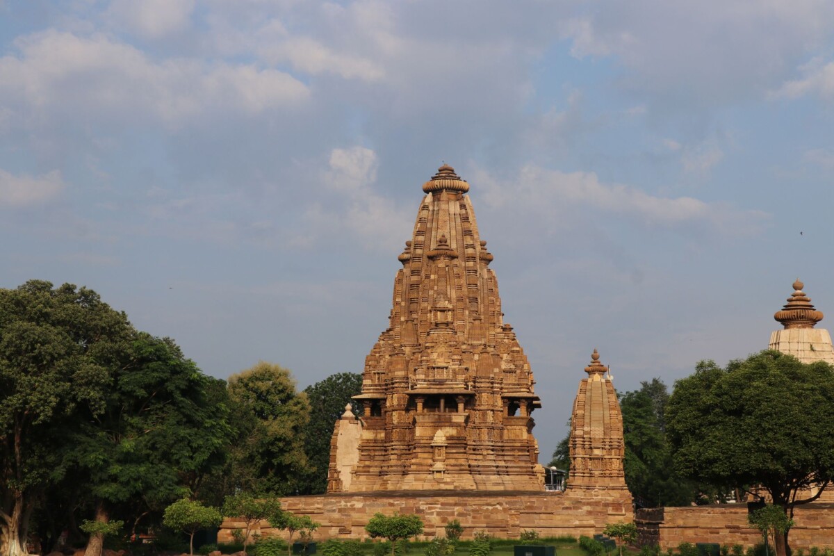 stunning view of the ancient khajuraho temple surrounded by lush greenery under | Two Scots Abroad Stunning view of the ancient Khajuraho Temple surrounded by lush greenery under a blue sky.